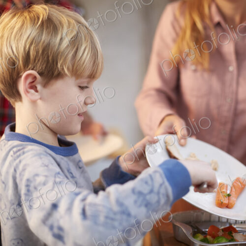 A young boy helping to clear the plates after a meal in a family kitchen.