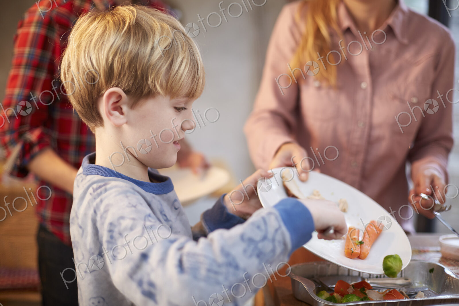 A young boy helping to clear the plates after a meal in a family kitchen.