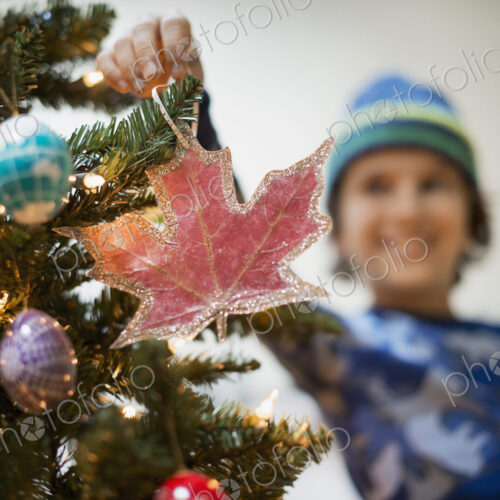 A young boy holding Christmas ornaments and placing them on the Christmas tree. A young boy holding Christmas ornaments and placing them on the Christmas tree.