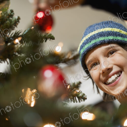 A young boy holding Christmas ornaments and placing them on the Christmas tree. A young boy holding Christmas ornaments and placing them on the Christmas tree.