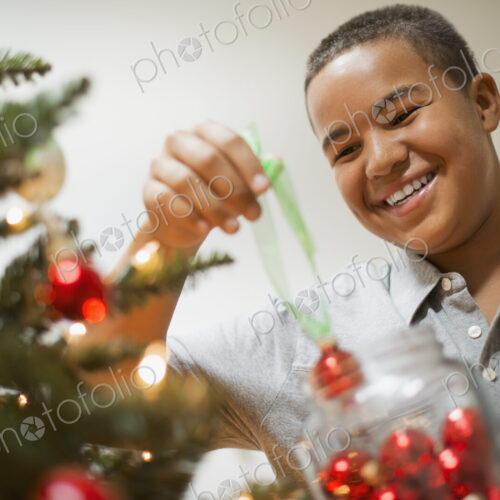 A young boy holding Christmas ornaments and placing them on the Christmas tree. A young boy holding Christmas ornaments and placing them on the Christmas tree.