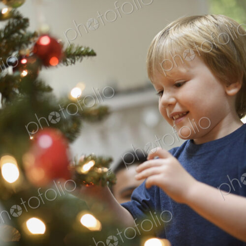 A young boy holding Christmas ornaments and placing them on the Christmas tree. A young boy holding Christmas ornaments and placing them on the Christmas tree.