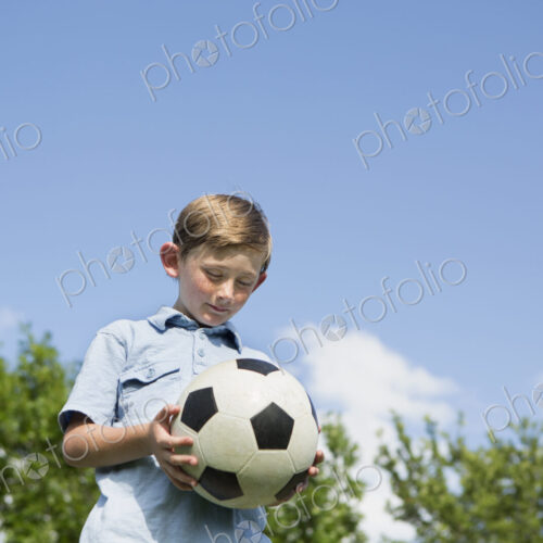 A young boy holding a soccer ball.