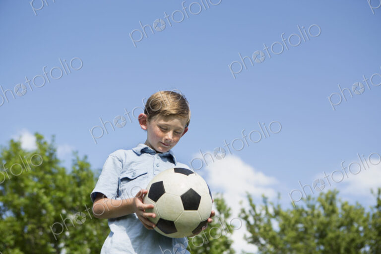 A young boy holding a soccer ball.