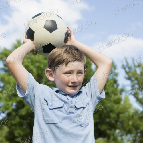 A young boy holding a soccer ball above his head. A young boy holding a soccer ball above his head.