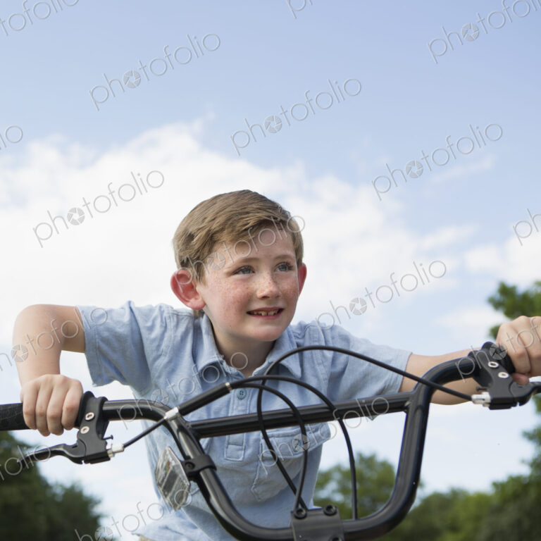 A young boy leaning over the handlebars of a bicycle.