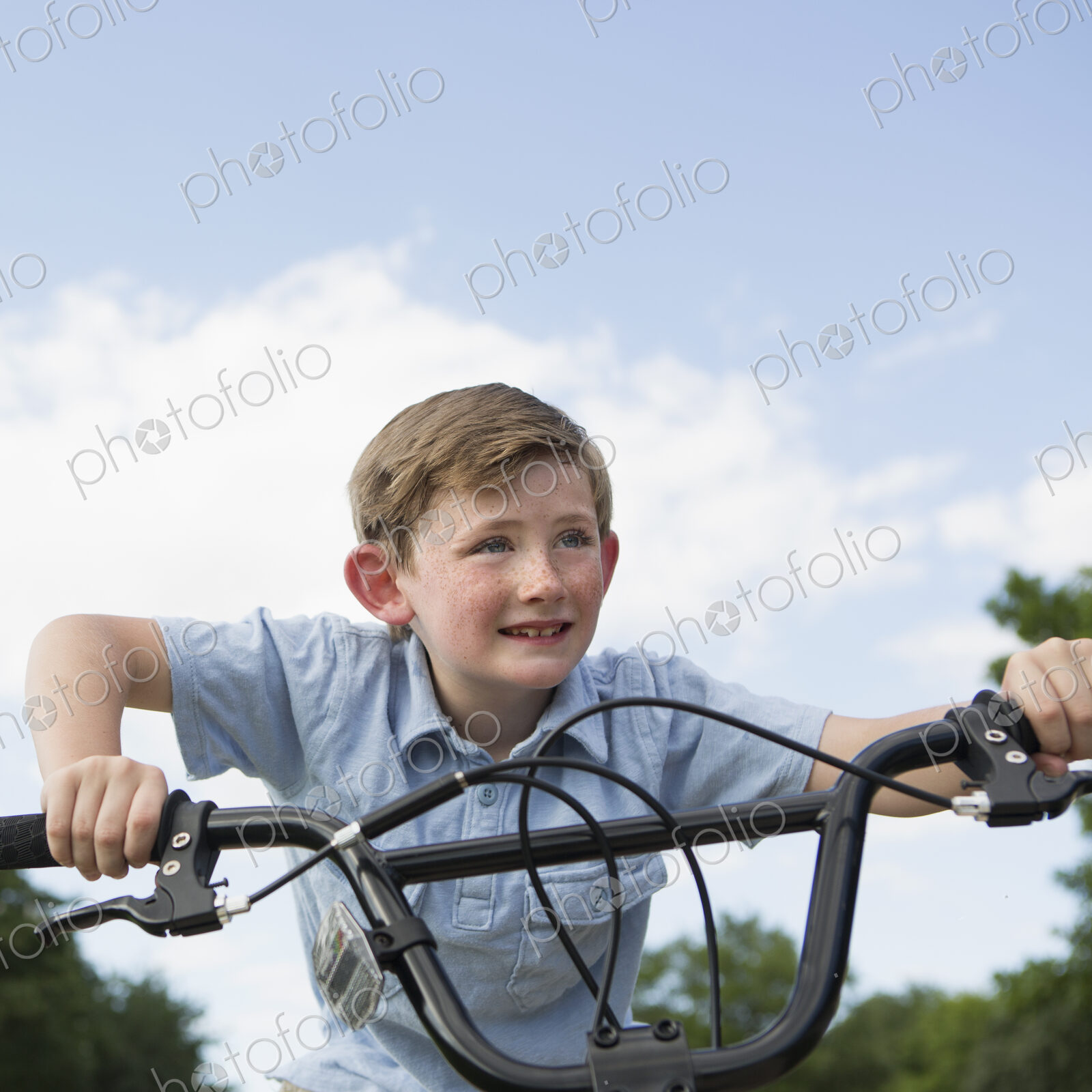 A young boy leaning over the handlebars of a bicycle.