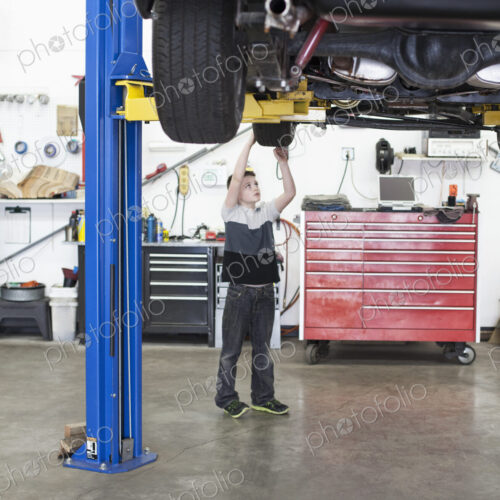 A young boy looks at a car tire in his dad's classic car repair shop.