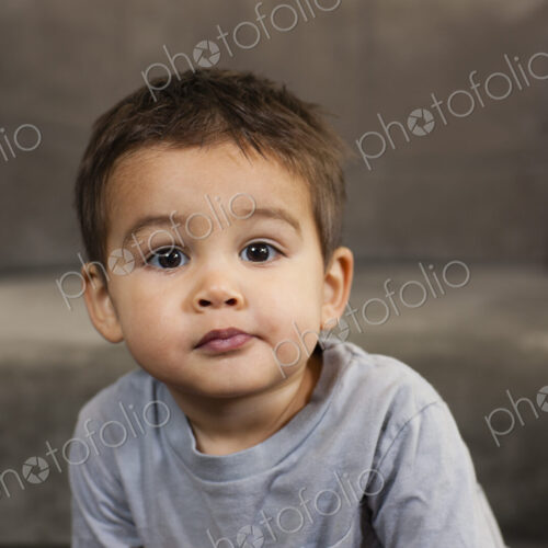 A young boy sitting looking at the camera with a serious expression. A young boy sitting looking at the camera with a serious expression.