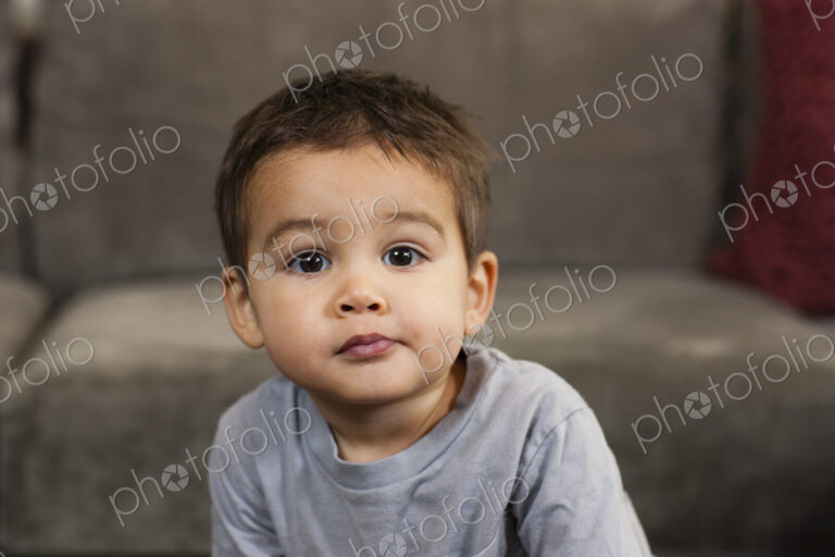 A young boy sitting looking at the camera with a serious expression.