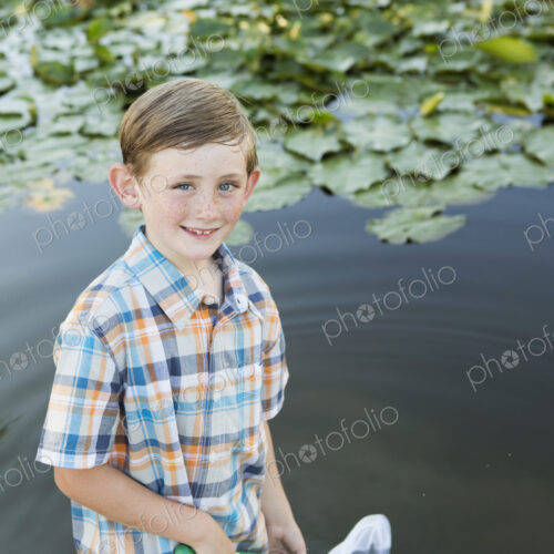 A young boy standing in shallow water with a fishing net.