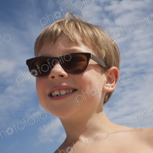 A young boy wearing sunglasses. A young boy wearing sunglasses.