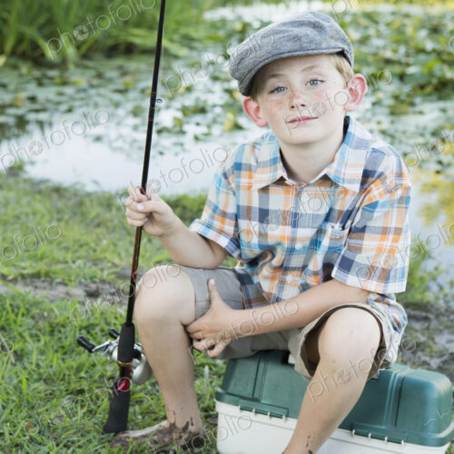 A young boy with his fishing road, by a lake or river. A young boy with his fishing road, by a lake or river.