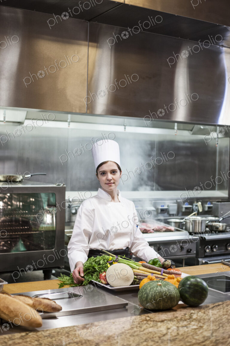 A young caucasian chef working with fresh vegetables in a commercial kitchen,