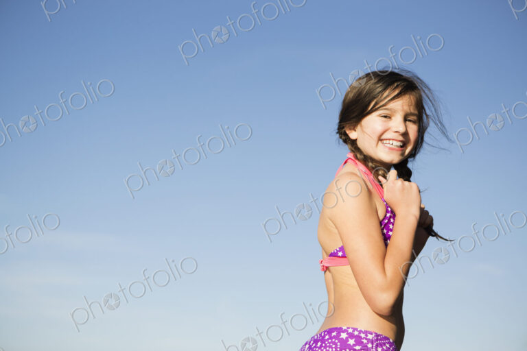 A young child in a bikini with plaited hair.