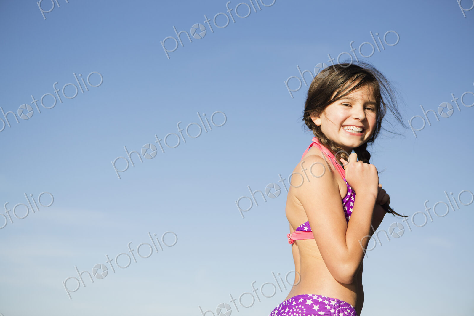 A young child in a bikini with plaited hair.