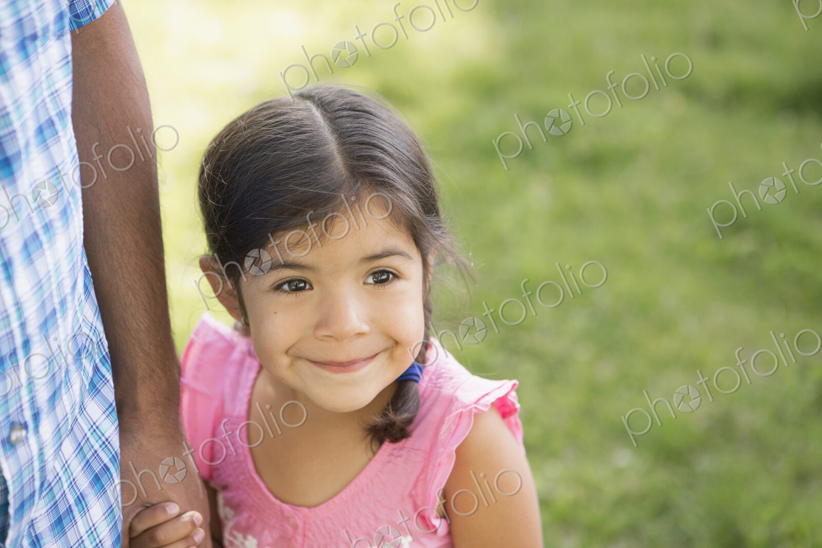 A young child in a pink dress holding her father’s hand.