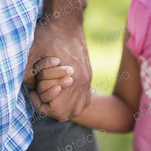 A young child in a pink dress holding her father's hand. A young child in a pink dress holding her father's hand.