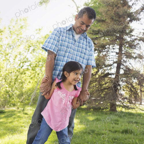 A young child in a pink dress with her feet on her father's feet. A young child in a pink dress with her feet on her father's feet.