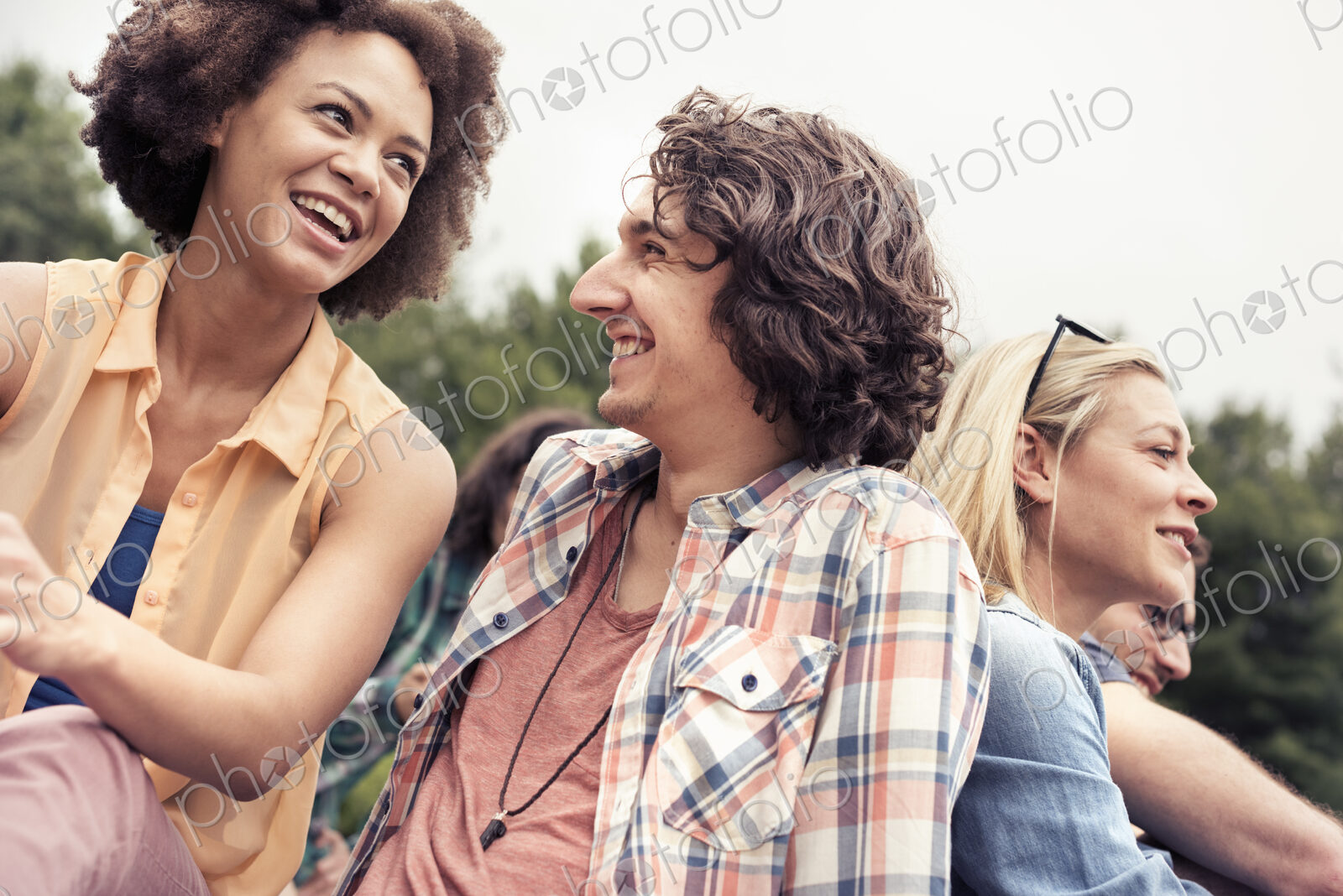 A young couple, a man and woman among others outdoors in the countryside.
