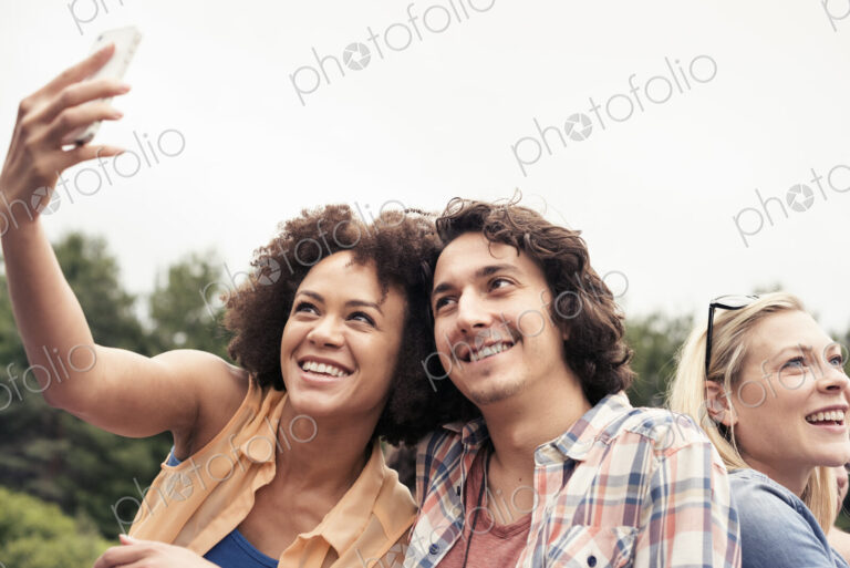 A young couple, a man and woman taking a selfie with a smart phone.