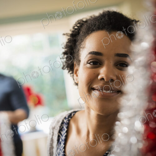 A young couple hanging tinsel up, decorating a house at Christmas.