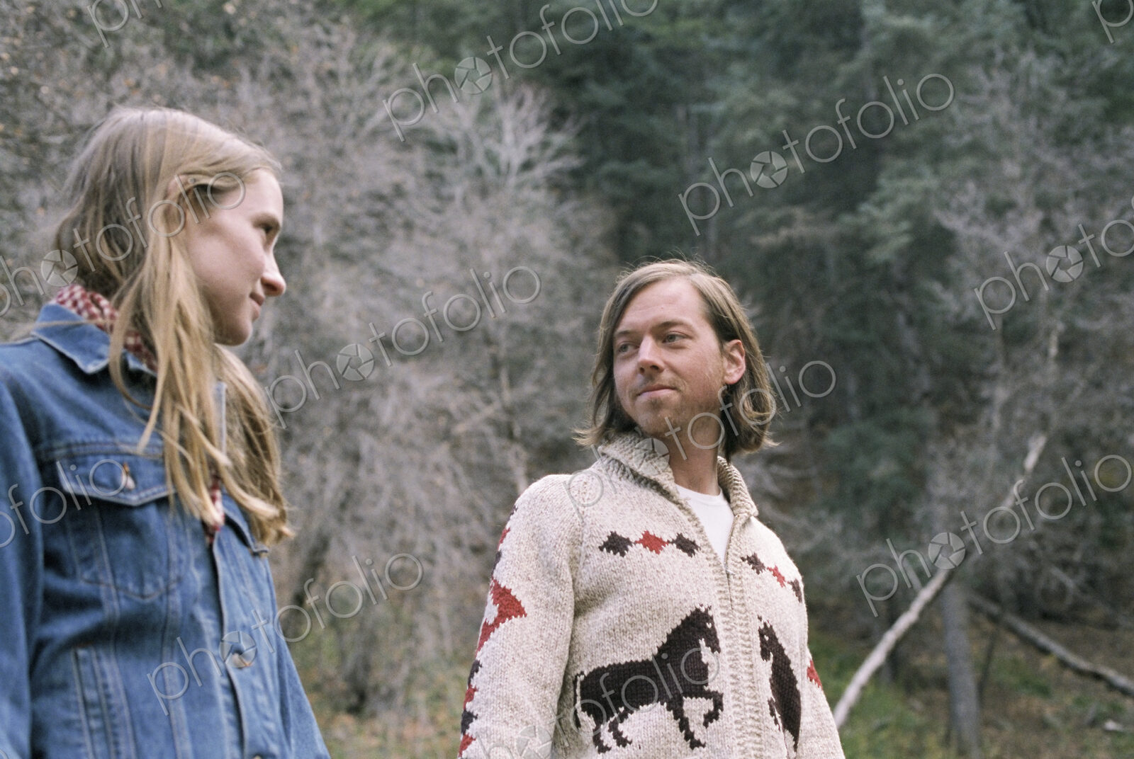 A young couple standing in a forest.
