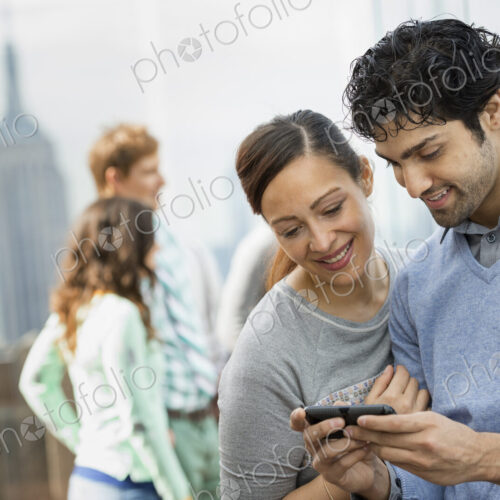 A young couple taking photographs with a mobile phone above a city