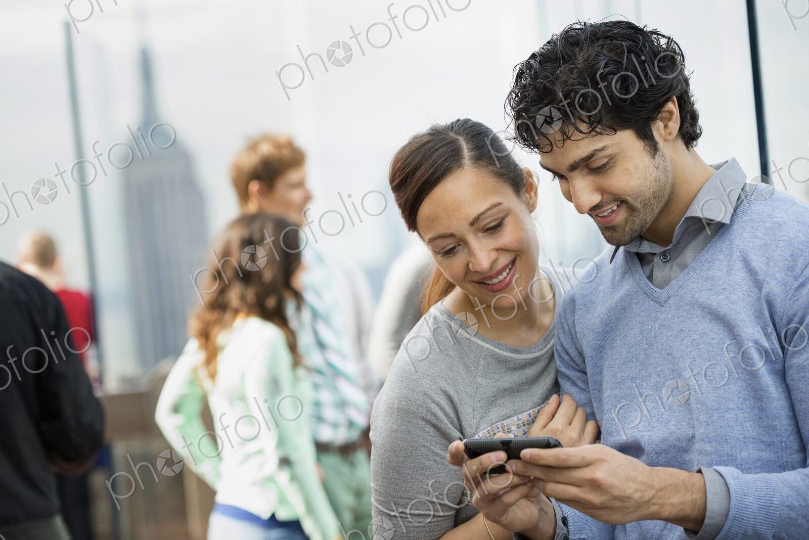 A young couple taking photographs with a mobile phone above a city