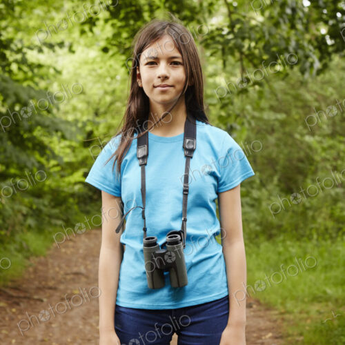 A young girl, a birdwatcher in a wood with binoculars around her neck. A young girl, a birdwatcher in a wood with binoculars around her neck.