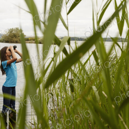 A young girl, a birdwatcher with binoculars.