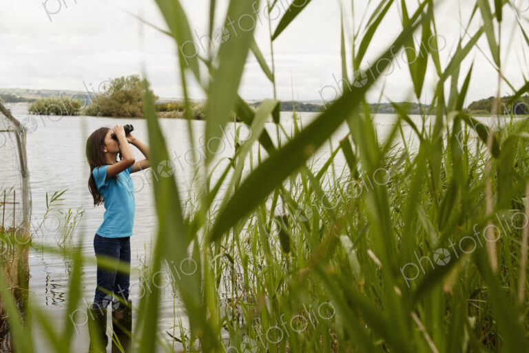 A young girl, a birdwatcher with binoculars.