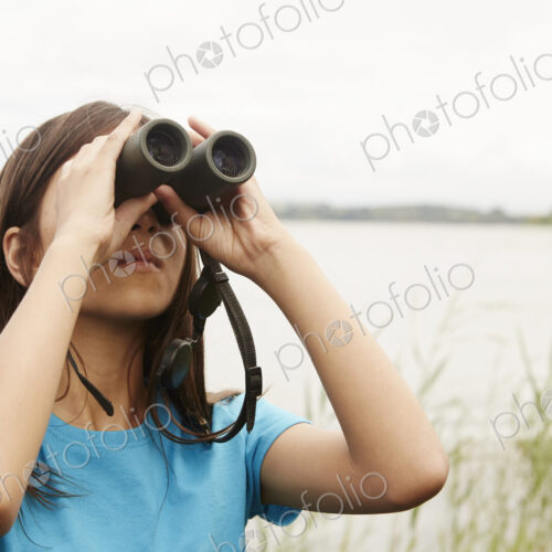 A young girl, a birdwatcher with binoculars.