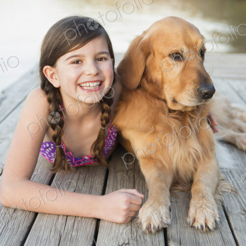 A young girl and a golden retriever dog lying on a jetty. A young girl and a golden retriever dog lying on a jetty.