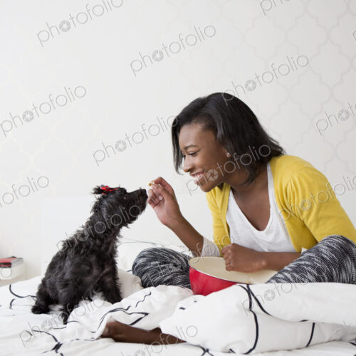 A young girl and her small black dog on a bed. A young girl and her small black dog on a bed.