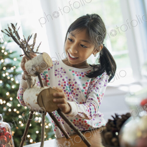 A young girl assembling a twig figure of a reindeer, making Christmas decorations. A young girl assembling a twig figure of a reindeer, making Christmas decorations.