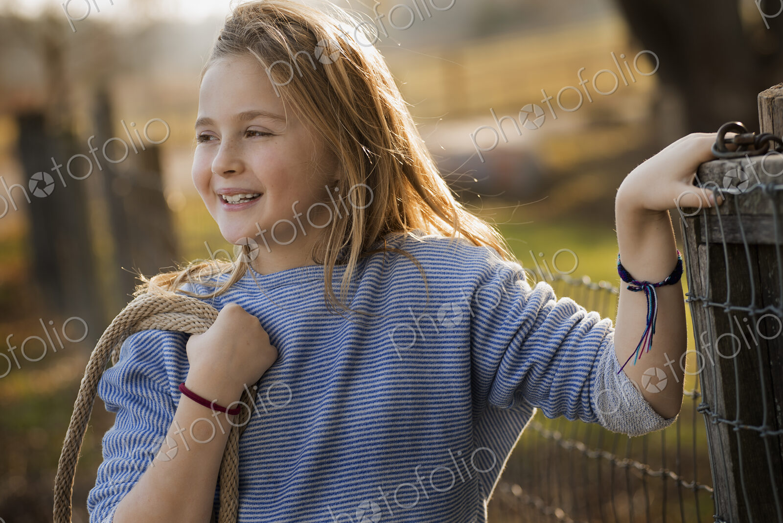 A young girl by a paddock fence.