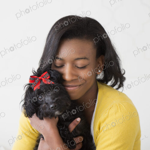 A young girl cuddling her small black pet dog. A young girl cuddling her small black pet dog.