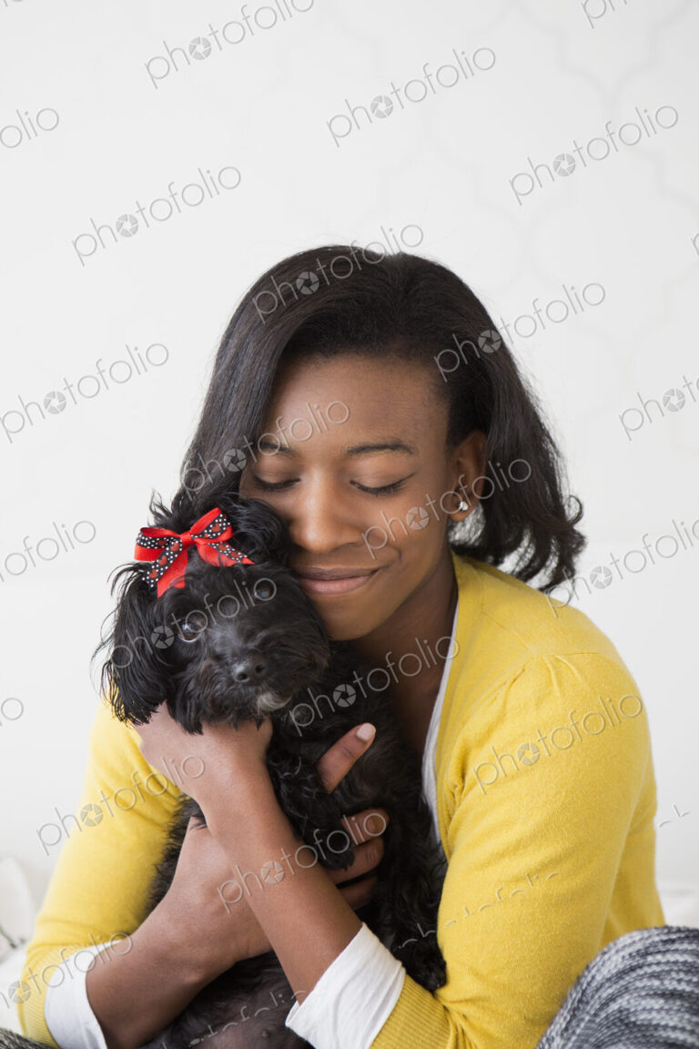 A young girl cuddling her small black pet dog.