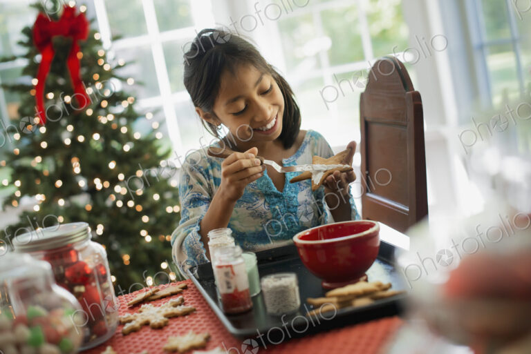 A young girl decorating Christmas cookies with icing.