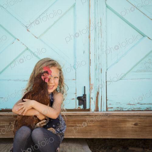 A young girl holding a chicken in her arms. A young girl holding a chicken in her arms.