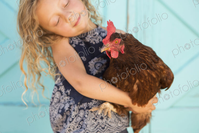 A young girl holding a chicken in her arms.