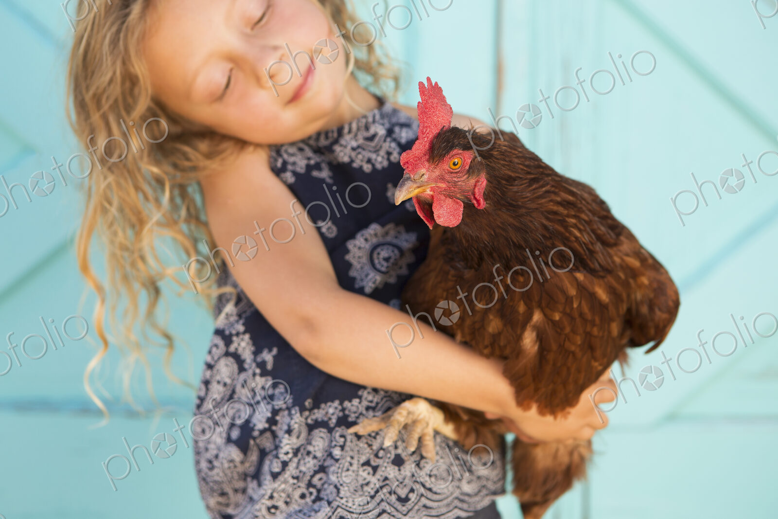 A young girl holding a chicken in her arms.