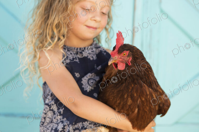 A young girl holding a chicken in her arms.