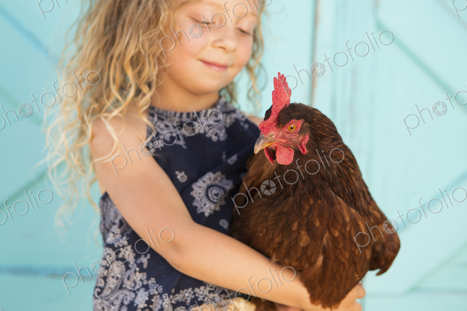 A young girl holding a chicken in her arms.