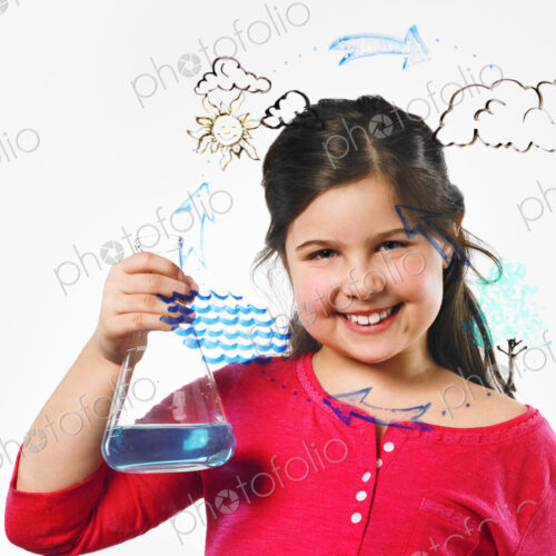 A young girl holding a conical flask of blue liquid in front of an evaporation cycle… A young girl holding a conical flask of blue liquid in front of an evaporation cycle…