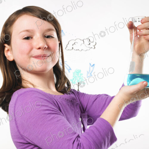 A young girl holding a conical flask of blue liquid in front of an evaporation cycle… A young girl holding a conical flask of blue liquid in front of an evaporation cycle…