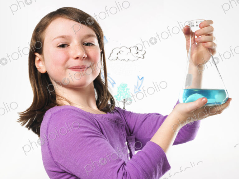 A young girl holding a conical flask of blue liquid in front of an evaporation cycle…