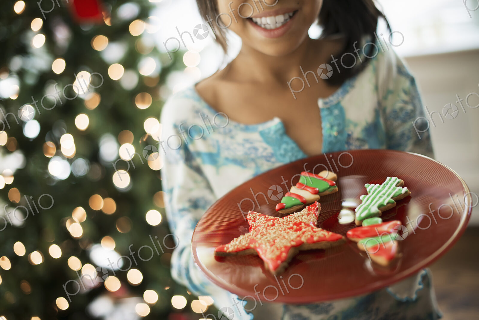 A young girl holding a plate of organic decorated Christmas cookies.