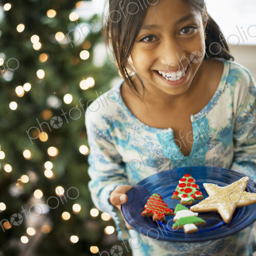 A young girl holding a plate of organic decorated Christmas cookies